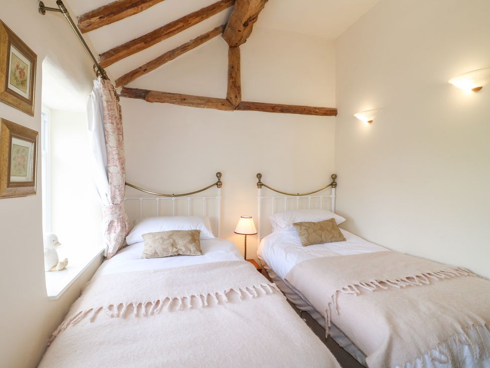 A bedroom with two beds and a window at Rose Cottage in Hartington