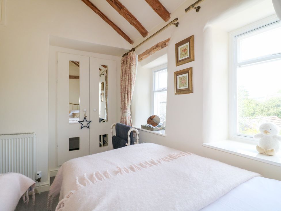 A bedroom with a bed and windows at Rose Cottage in Hartington