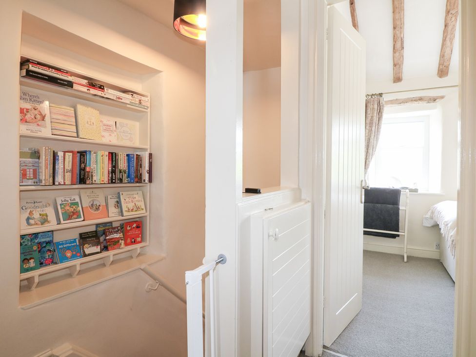 A hallway with a bookshelf and light fixture at Rose Cottage in Hartington