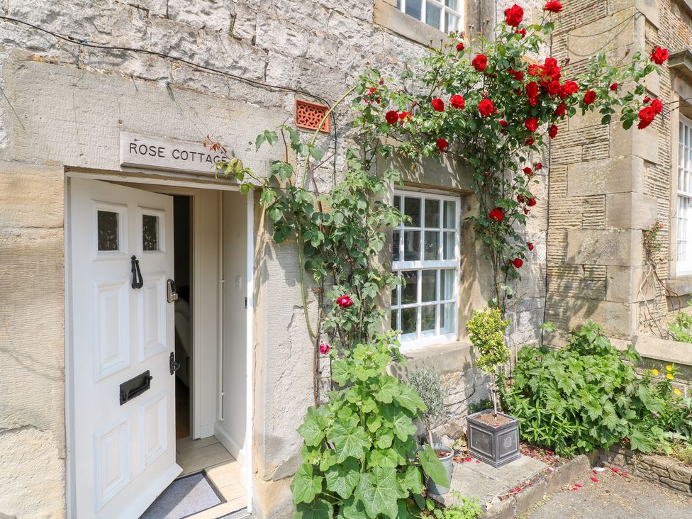 An entrance with a white door and roses at Rose Cottage in Hartington