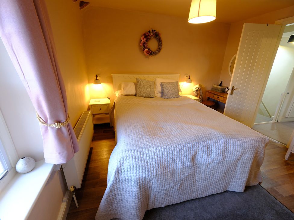 A bedroom with a bed and nightstand at Rose Cottage in Hartington