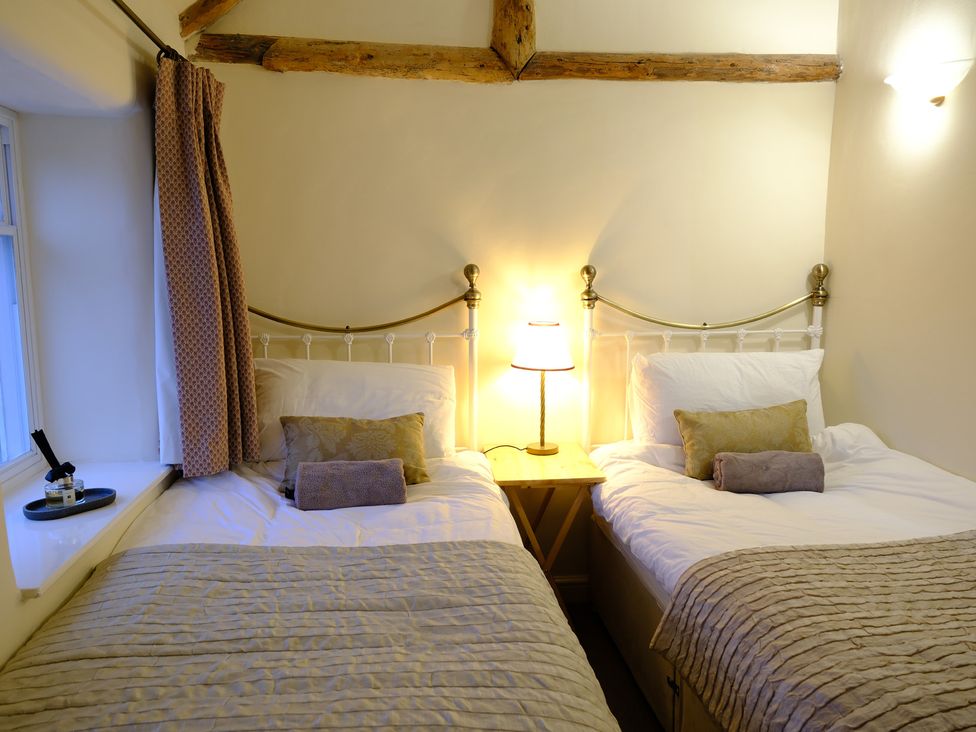 A bedroom with two beds and a lamp at Rose Cottage in Hartington