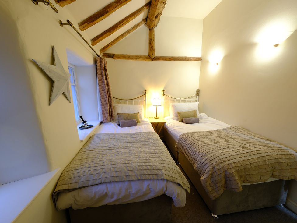 A bedroom with two beds and a lamp at Rose Cottage in Hartington