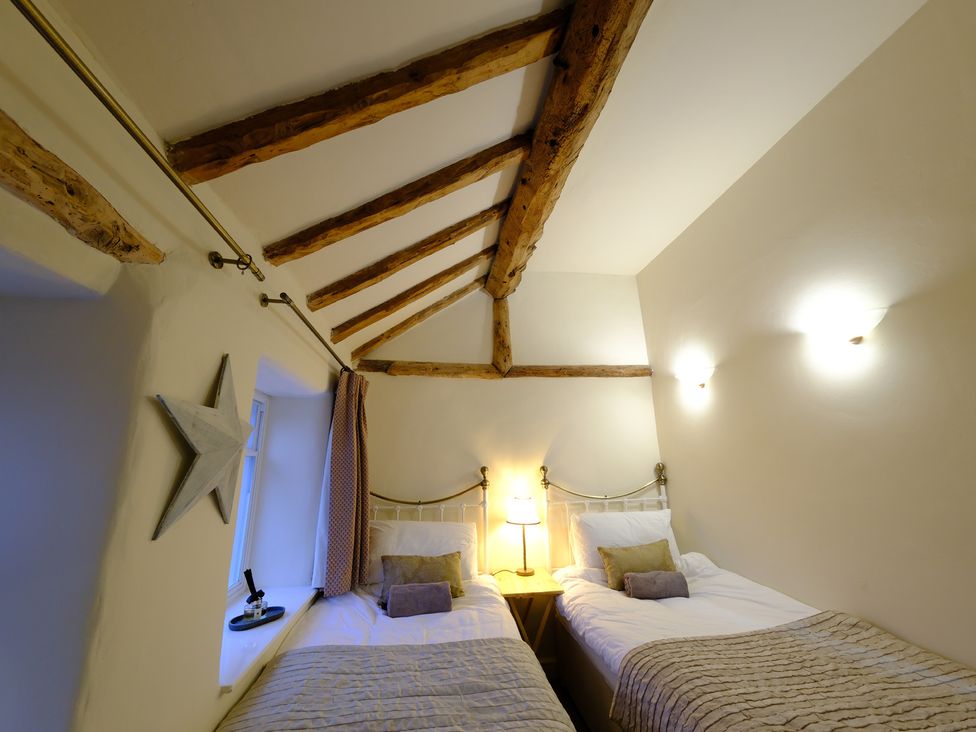 A bedroom with two beds and a bedside table at Rose Cottage in Hartington