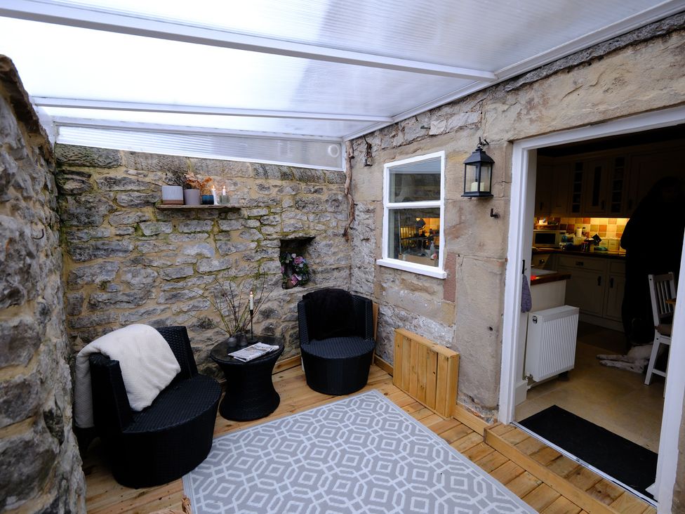 A conservatory with seating and a small table at Rose Cottage in Hartington