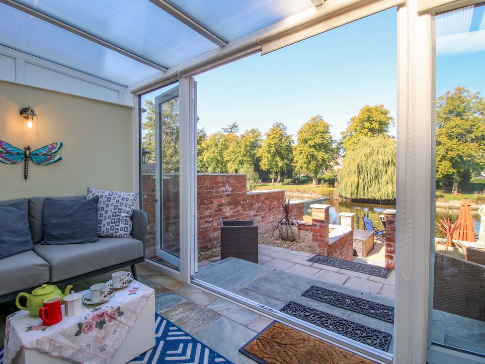 A conservatory with a sofa and tea set at Riverside Cottage in Shrewsbury