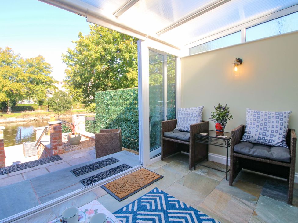 A conservatory with seating and a view of the water at Riverside Cottage in Shrewsbury