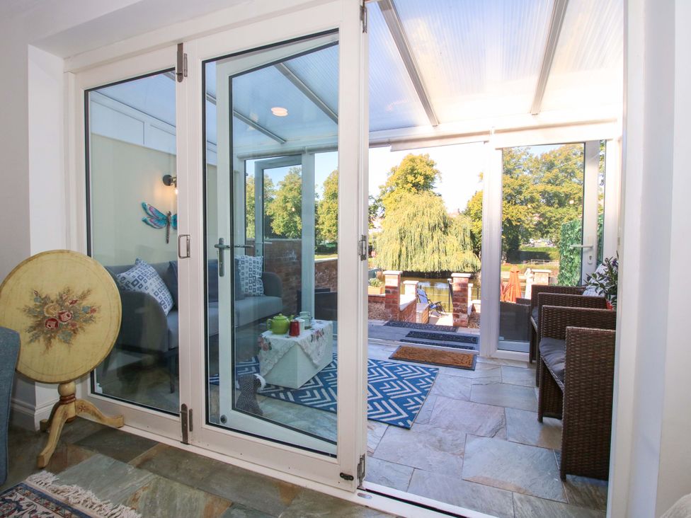 A conservatory with sliding doors leading to outdoor area at Riverside Cottage in Shrewsbury