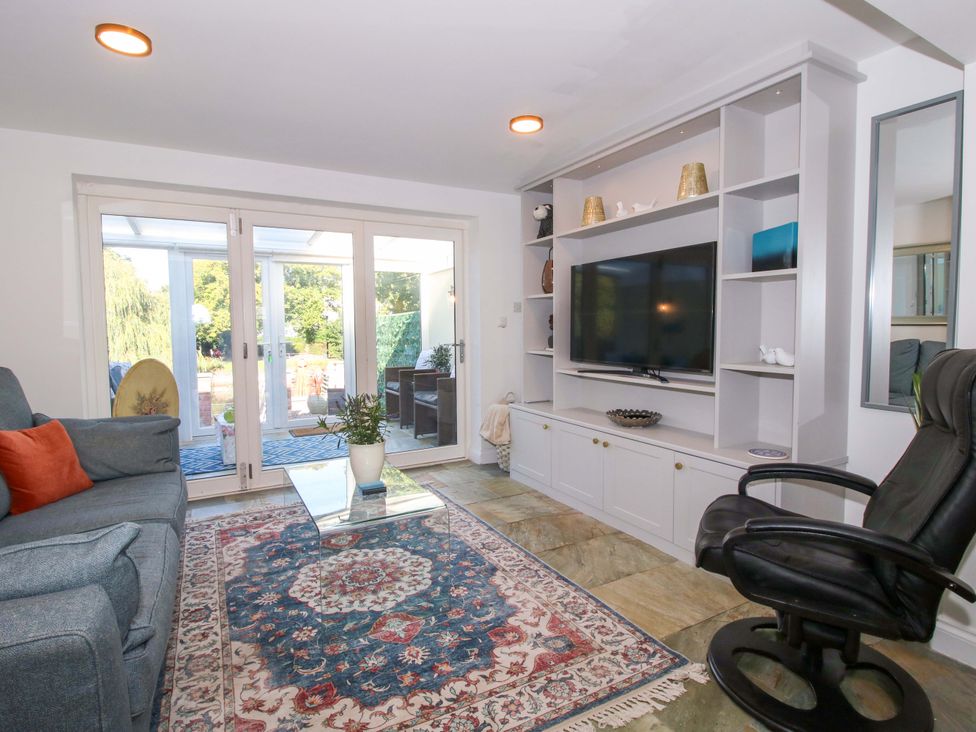 A living room with a television on a shelf and a sofa at Riverside Cottage in Shrewsbury