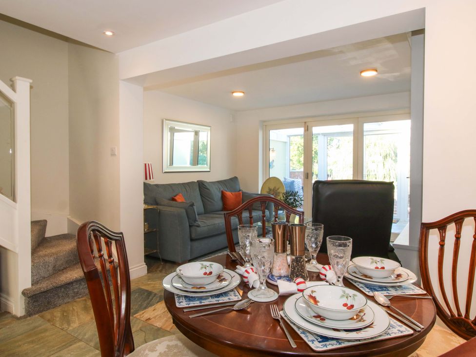 A dining area with a table set for a meal and a couch in Riverside Cottage Shrewsbury