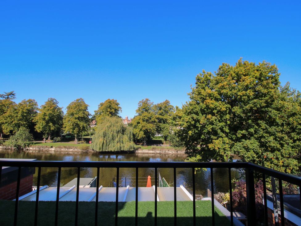 A view of a river with trees and a balcony at Riverside Cottage in Shrewsbury