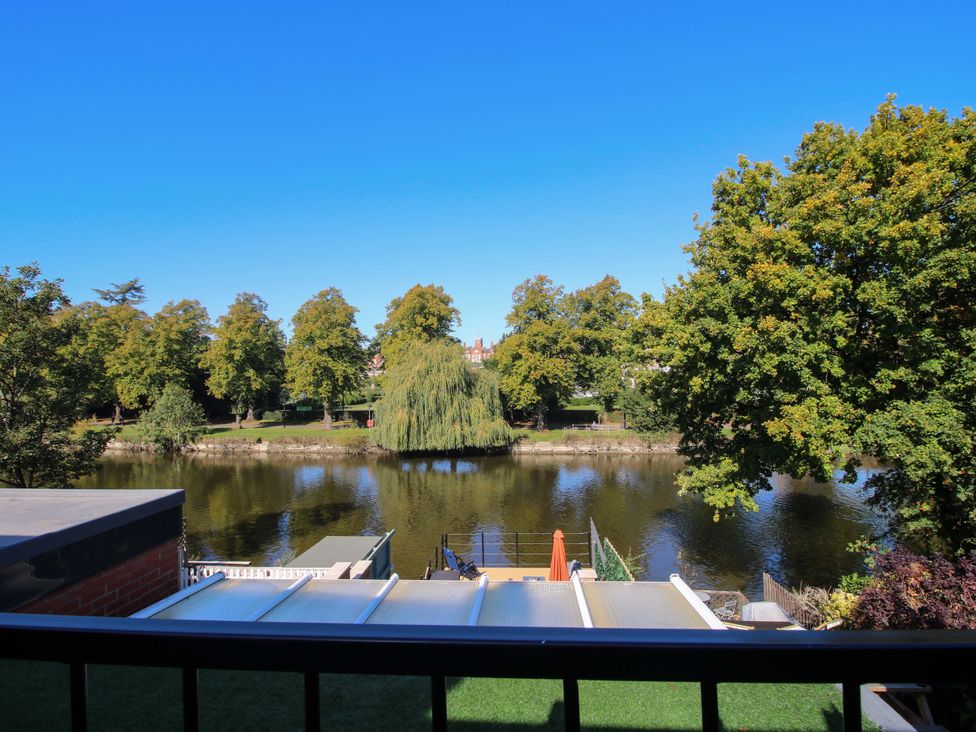 View from a balcony overlooking a river and trees at Riverside Cottage in Shrewsbury