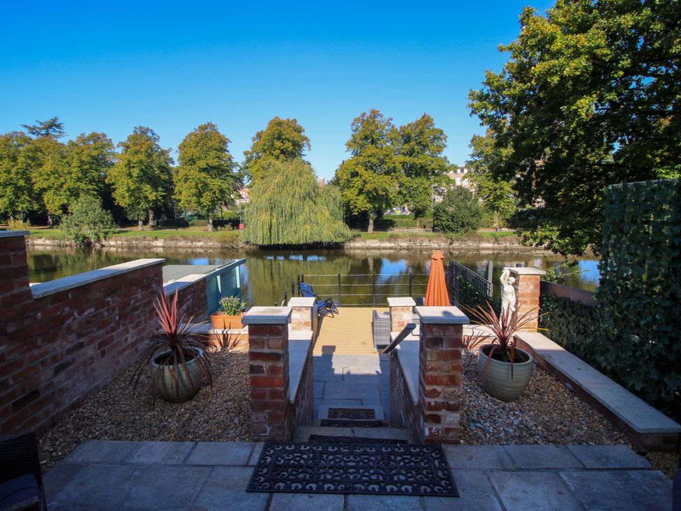 A garden with steps leading to a river and trees at Riverside Cottage in Shrewsbury