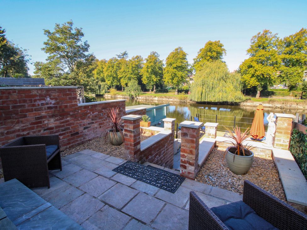 A garden with a river view and seating area at Riverside Cottage in Shrewsbury