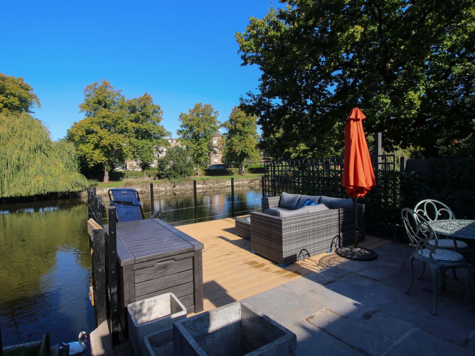 An outdoor area with a deck, sofa, and water view at Riverside Cottage in Shrewsbury