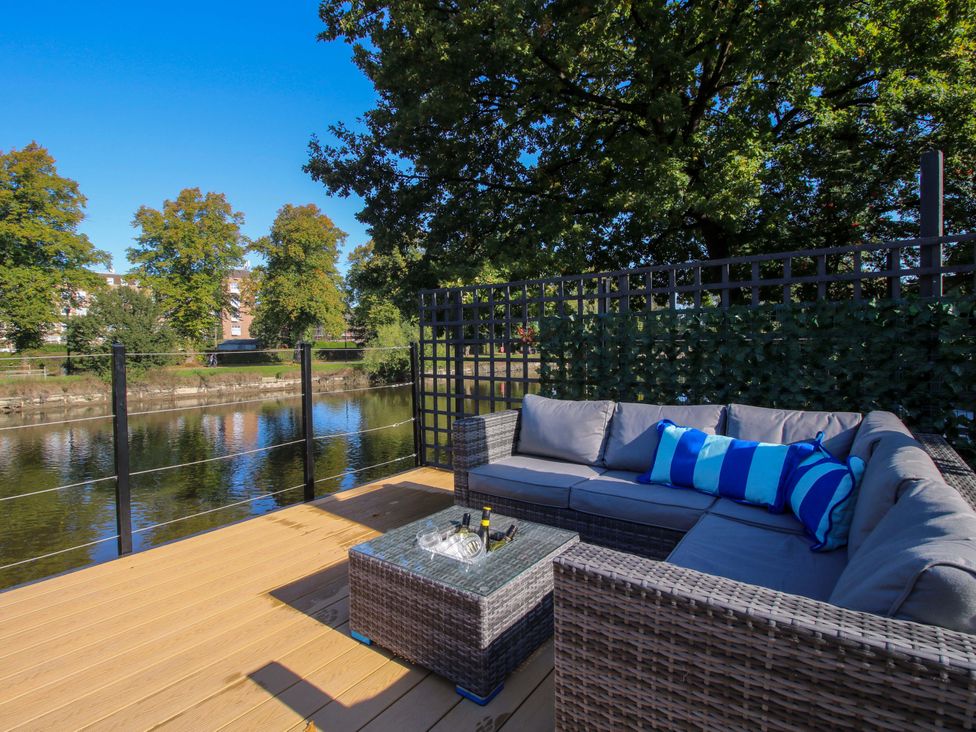 An outdoor seating area with a coffee table beside a river at Riverside Cottage in Shrewsbury