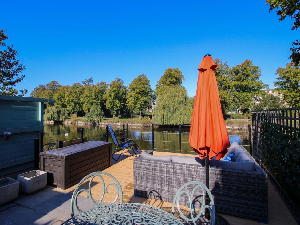 An outdoor area with furniture and a river view at Riverside Cottage in Shrewsbury