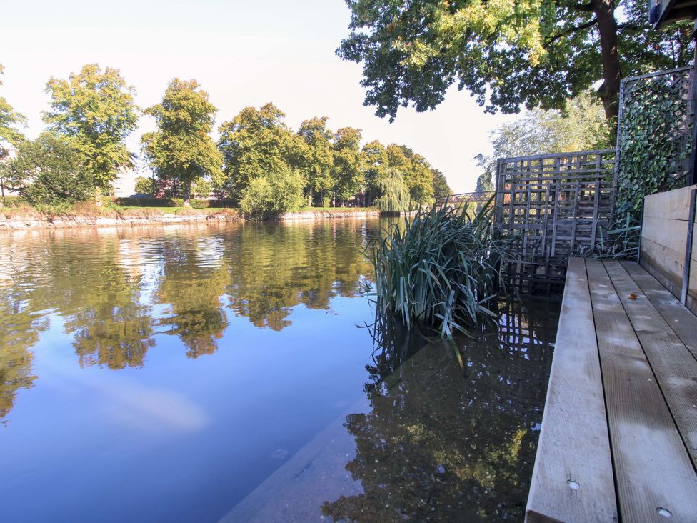 A water view with a wooden deck and plants at Riverside Cottage in Shrewsbury