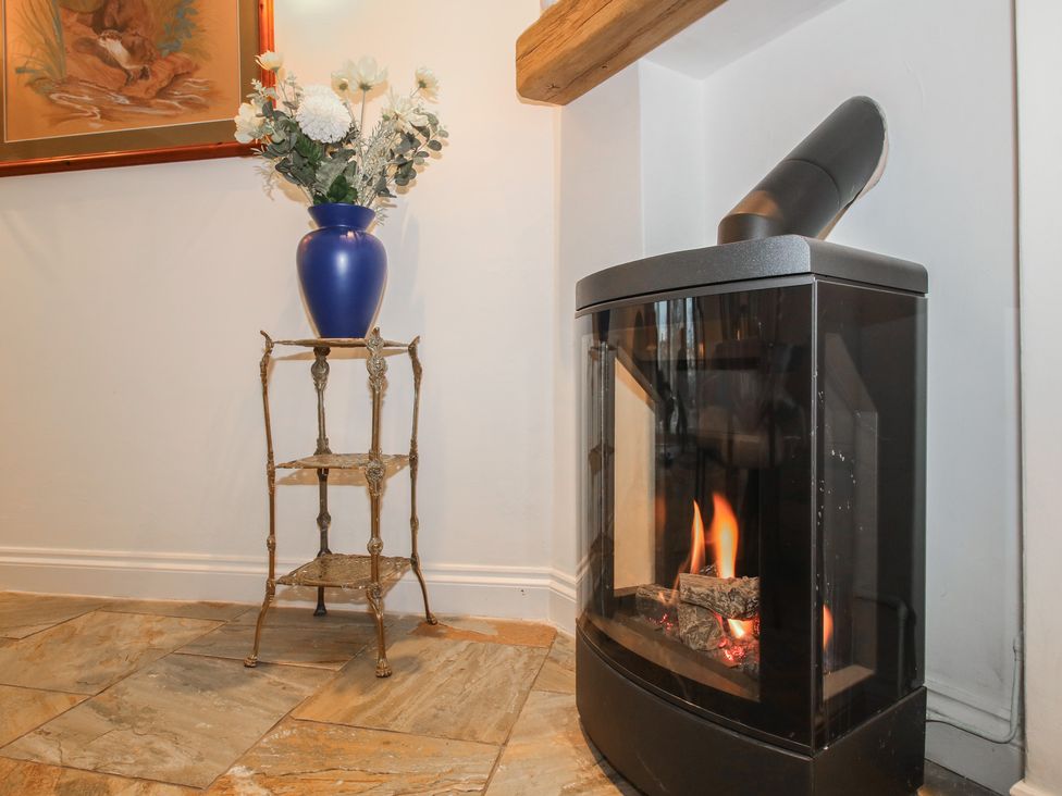 A living room with a fireplace and a flower vase at Riverside Cottage in Shrewsbury