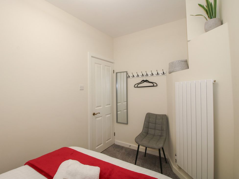 A bedroom with a bed, chair, and mirror at Riverside Cottage in Shrewsbury