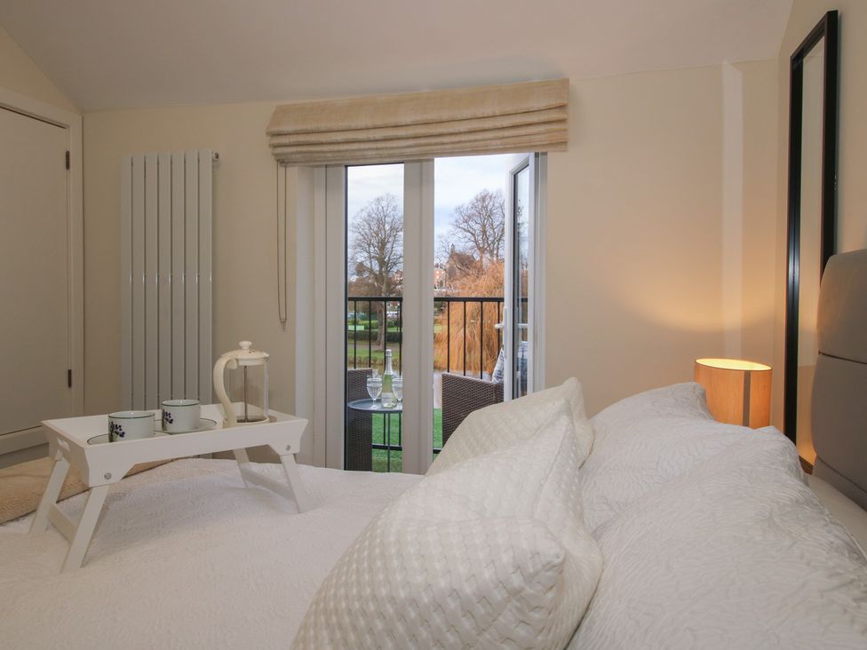 A bedroom with a bed and balcony at Riverside Cottage in Shrewsbury