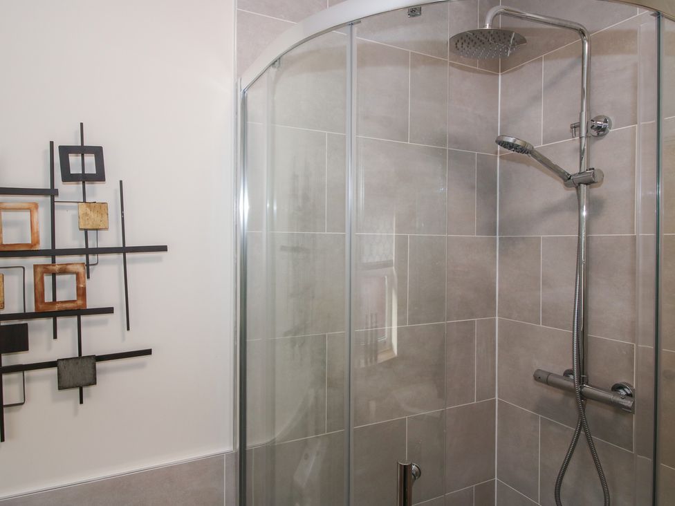 A shower with glass door and wall art at Riverside Cottage in Shrewsbury