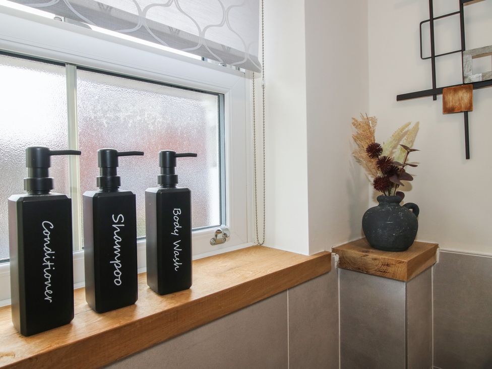 A bathroom with soap dispensers and a decorative vase at Riverside Cottage in Shrewsbury
