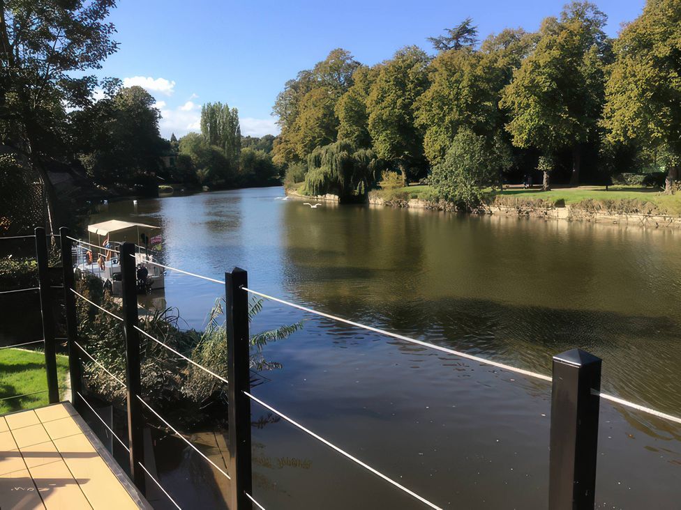 A view of a river with trees and a boat at Riverside Cottage in Shrewsbury