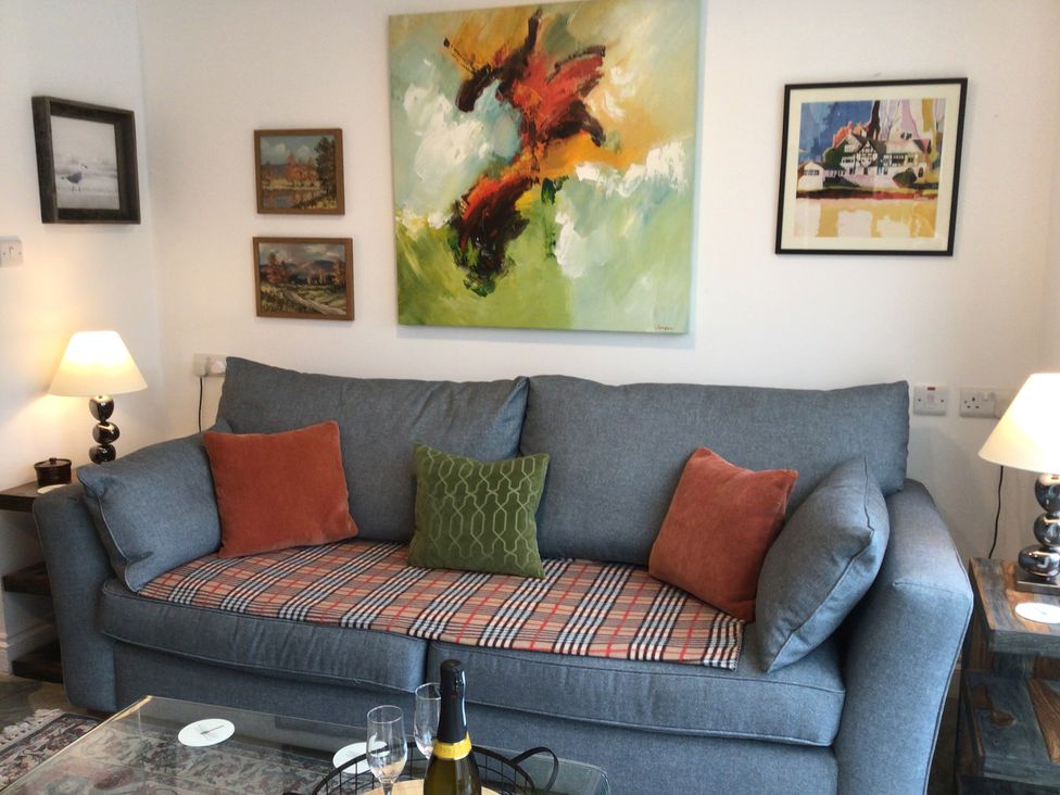 A living room with a sofa and paintings at Riverside Cottage in Shrewsbury