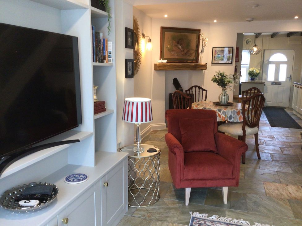 A living room with a television and dining area at Riverside Cottage in Shrewsbury