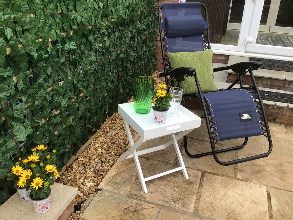 An outdoor seating area with a deck chair and flowers at Riverside Cottage in Shrewsbury