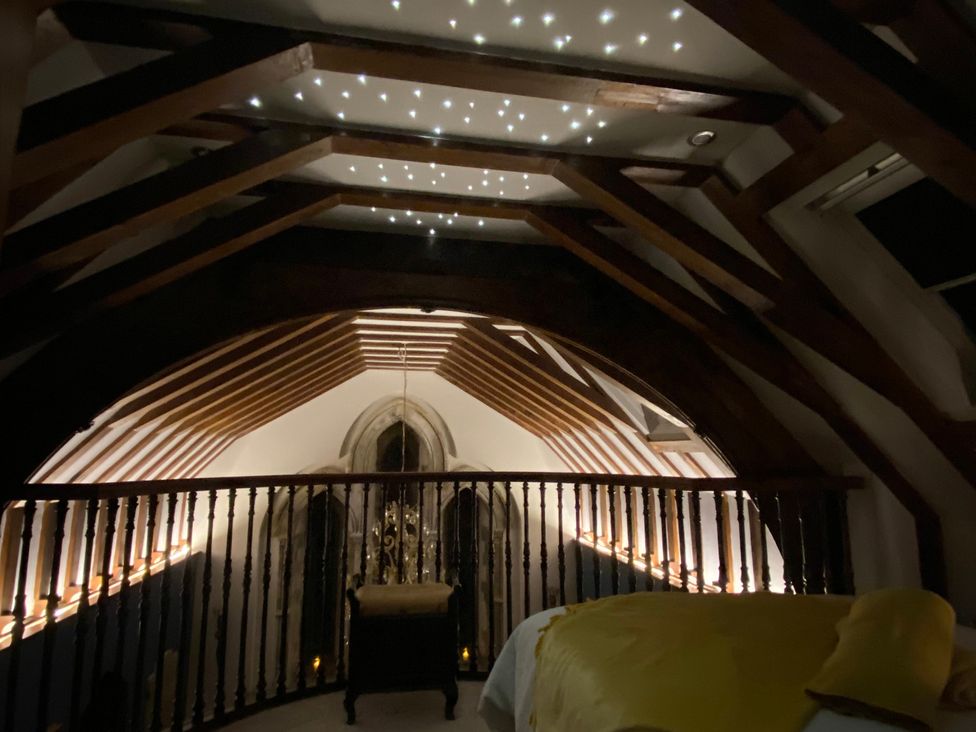 A loft with wooden beams and decorative lights at St Edmunds Church in Fraisthorpe