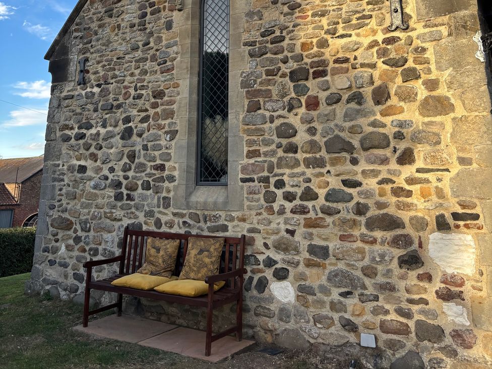 A stone wall with a bench and cushions at St Edmunds Church in Fraisthorpe