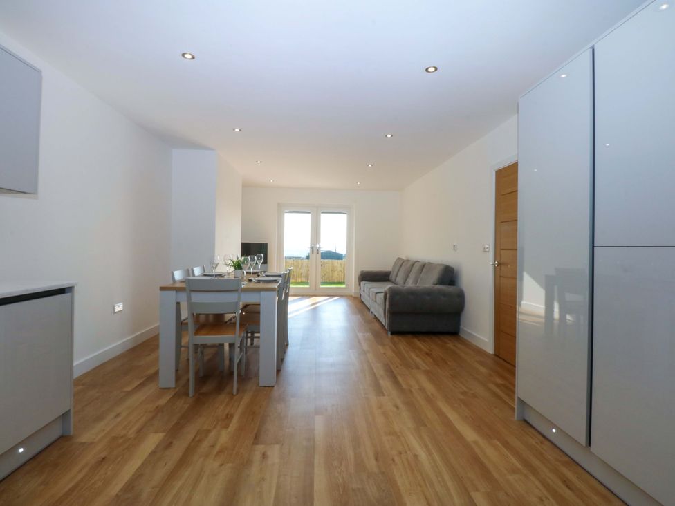 A living room with a dining table and couch at 15 Llys Tegeirian in Llangristiolus near Llangefni