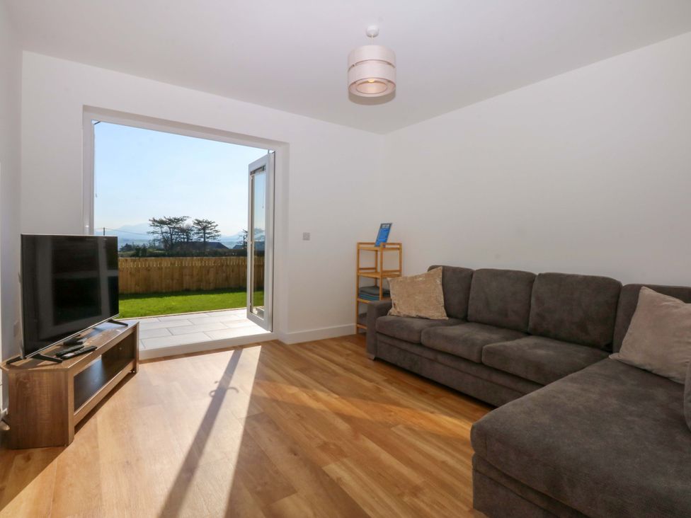 A living room with a sofa and television at 15 Llys Tegeirian in Llangristiolus near Llangefni