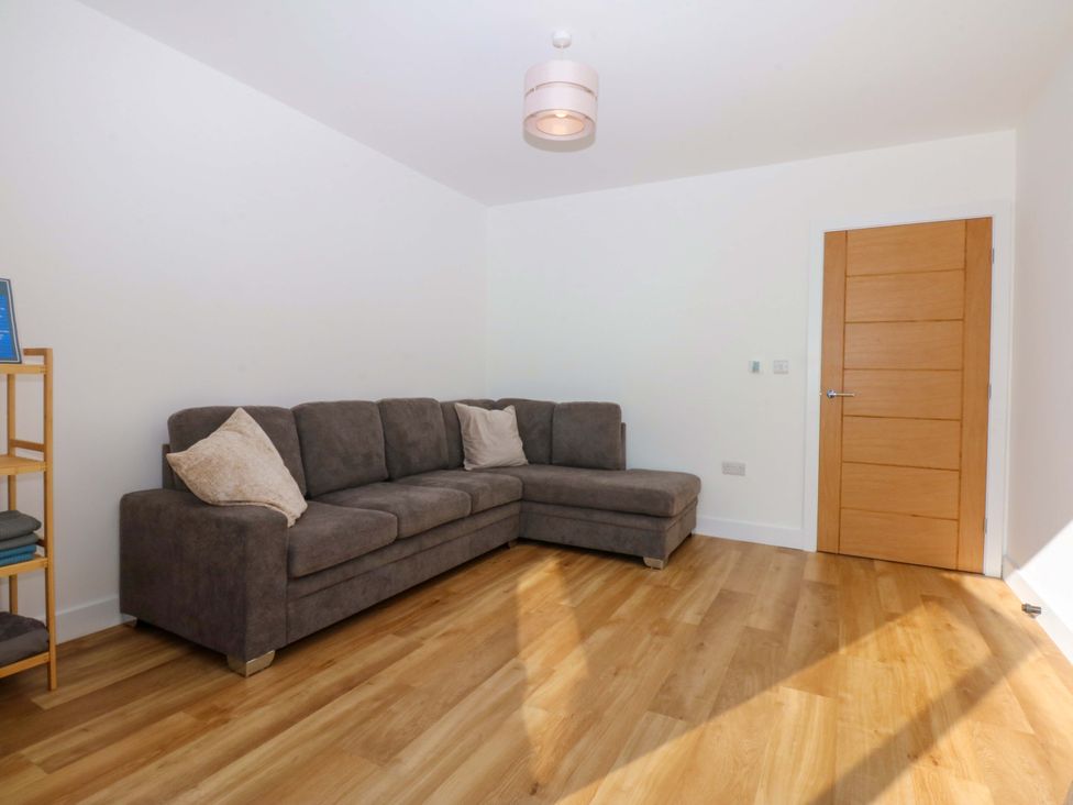 A living room with a sofa and shelf at 15 Llys Tegeirian Llangristiolus near Llangefni