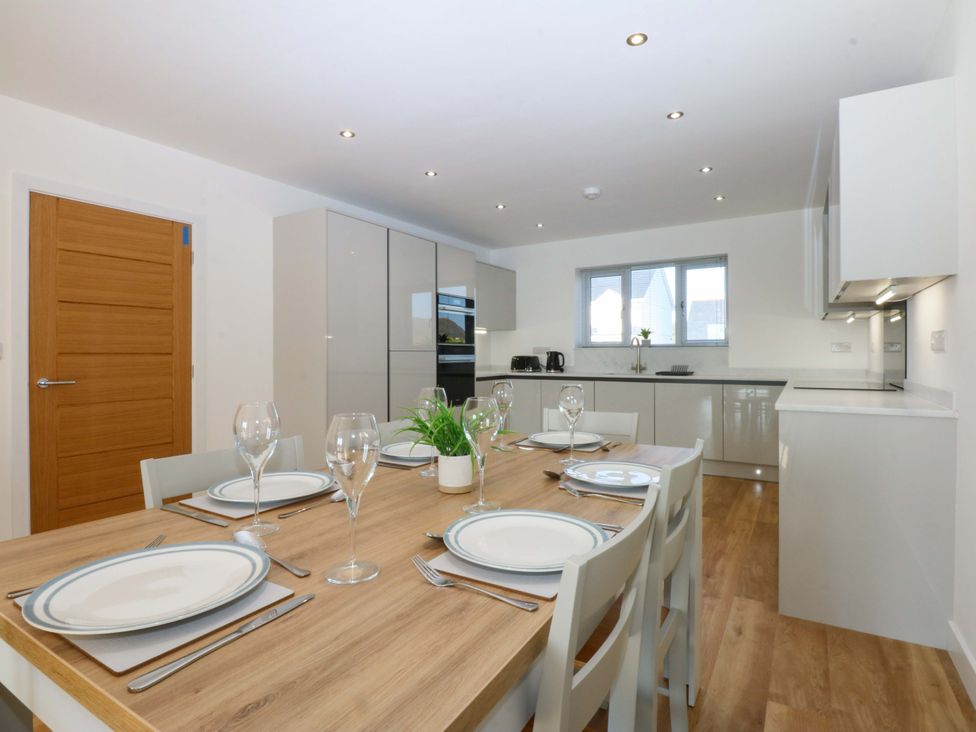 A kitchen with dining table and chairs at 15 Llys Tegeirian in Llangristiolus near Llangefni