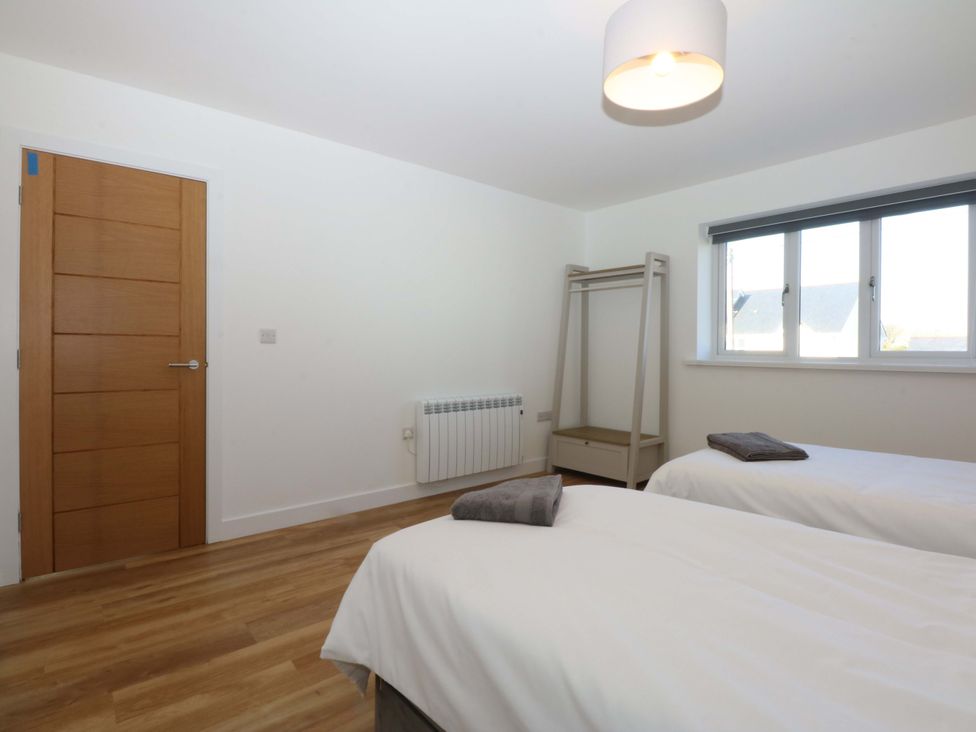 A bedroom with two beds and a hanging rack at 15 Llys Tegeirian in Llangristiolus near Llangefni