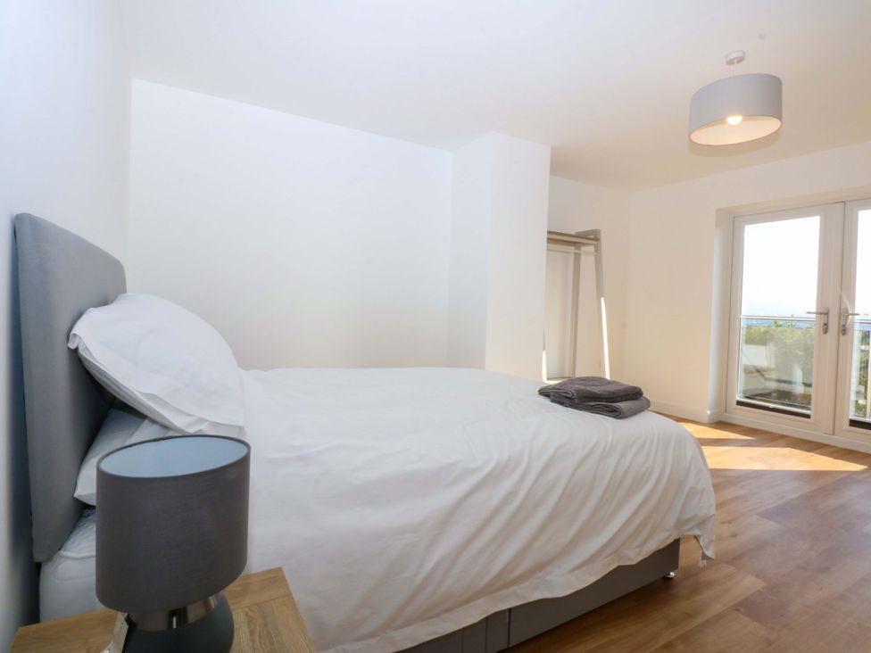 A bedroom with a bed and a clothes rail at 15 Llys Tegeirian in Llangristiolus near Llangefni