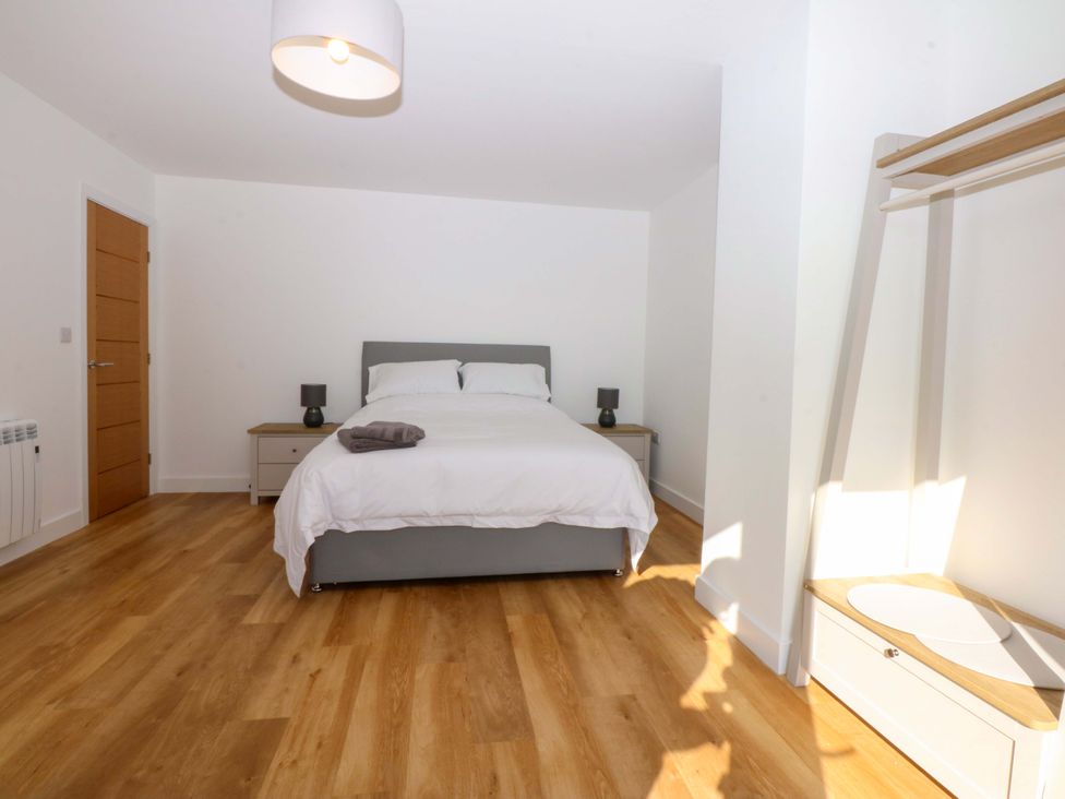 A bedroom with a bed and nightstand at 15 Llys Tegeirian in Llangristiolus near Llangefni