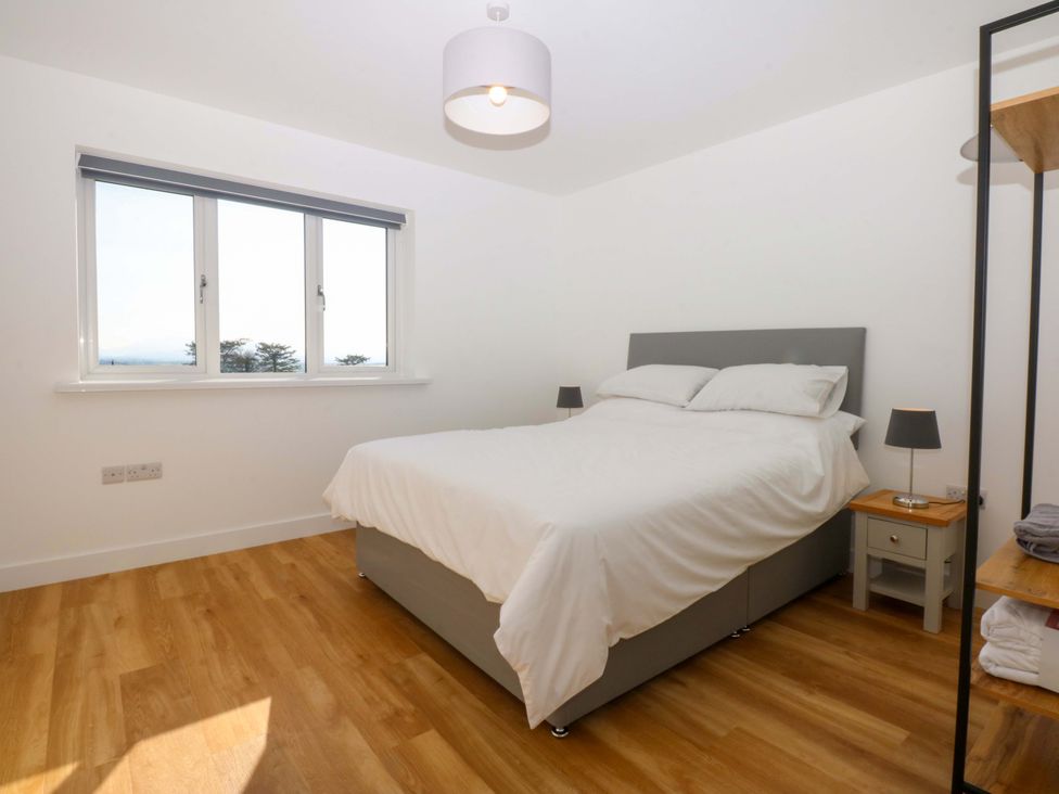 A bedroom with a bed and bedside table at 15 Llys Tegeirian in Llangristiolus near Llangefni