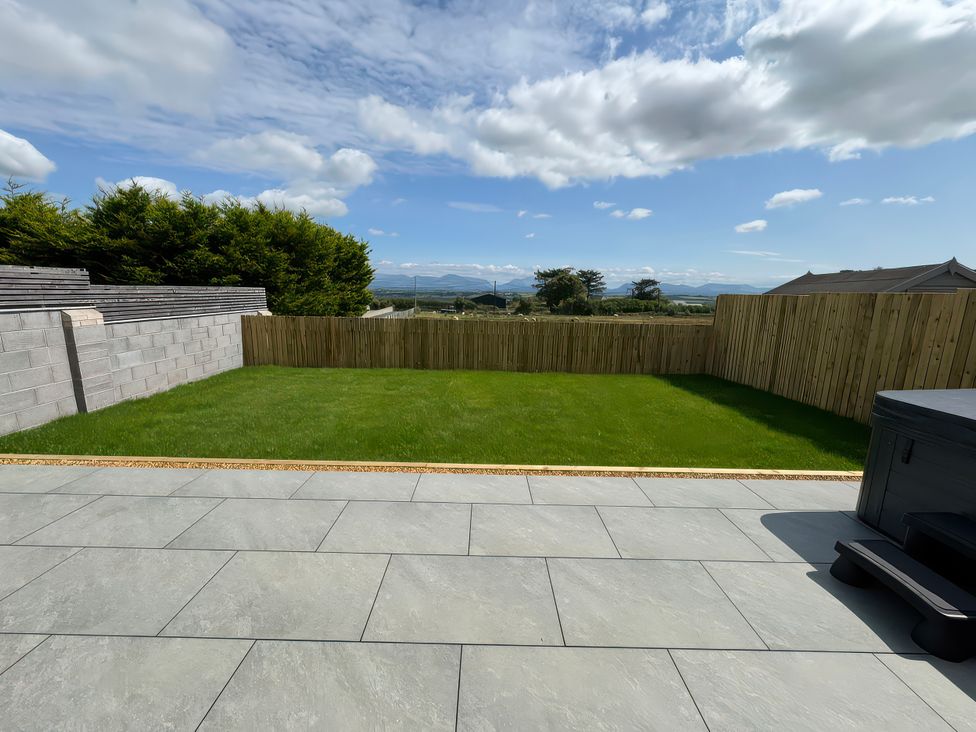 A garden with grass and a fence at 15 Llys Tegeirian in Llangristiolus near Llangefni