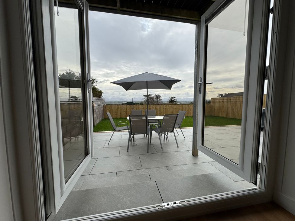 An outdoor area with a table and chairs under an umbrella at Golygfa in Llangristiolus near Llangefni
