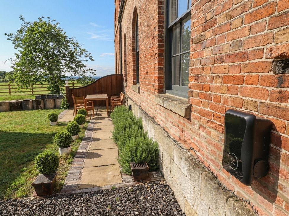 An outdoor area with a table and chairs beside a brick wall at West Stable in Grove near Retford