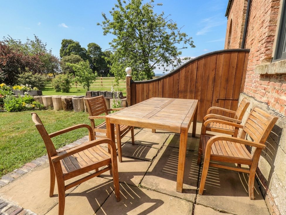 A patio with a wooden table and chairs at West Stable in Grove near Retford