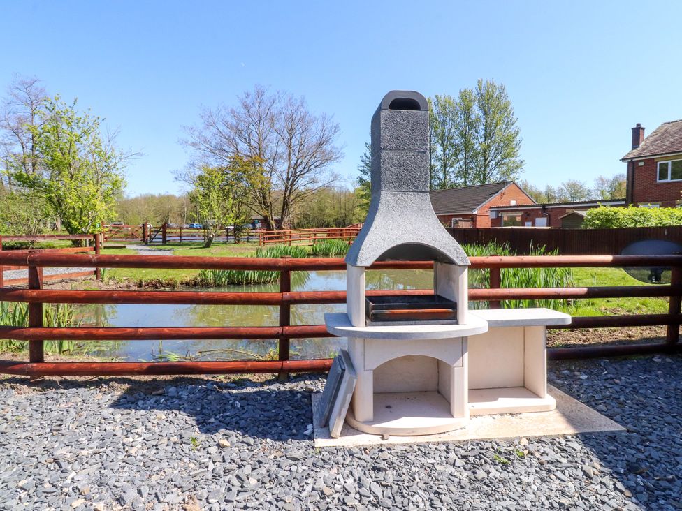 An outdoor area with a barbecue and a pond at Lakeview Lodge in Forton near Garstang
