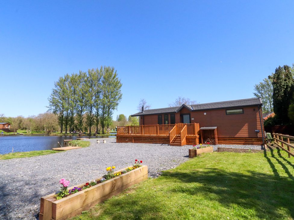 A lodge beside a lake with a deck at Lakeview Lodge in Forton near Garstang