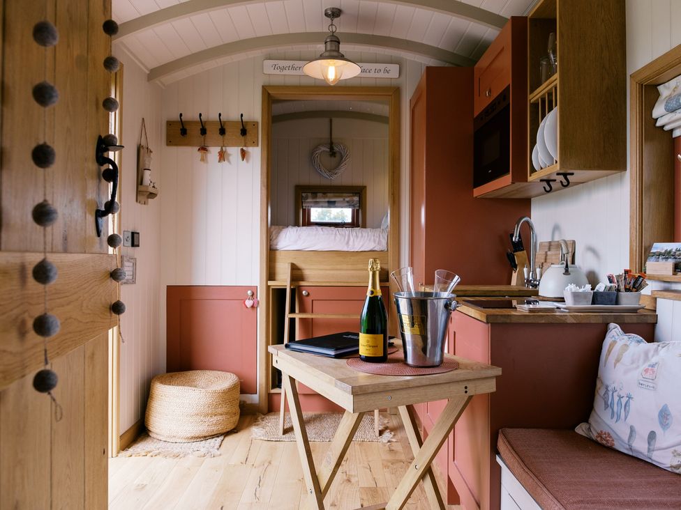An interior of a small accommodation with table and kitchen units at Bonnie's Shepherds Hut at Shepherds Lodge Retreat and Wellness Bottesford near Redmile and Vale of Belvoir