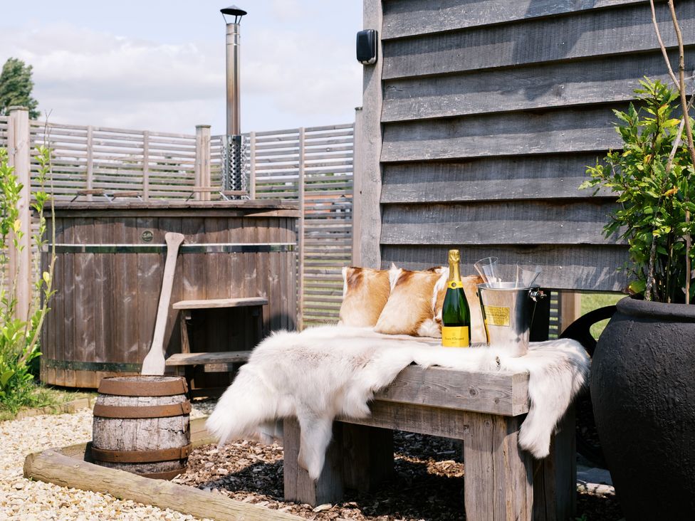 An outdoor space with a hot tub and a wooden table at Bonnie's Shepherds Hut at Shepherds Lodge Retreat and Wellness Bottesford near Redmile and Vale of Belvoir