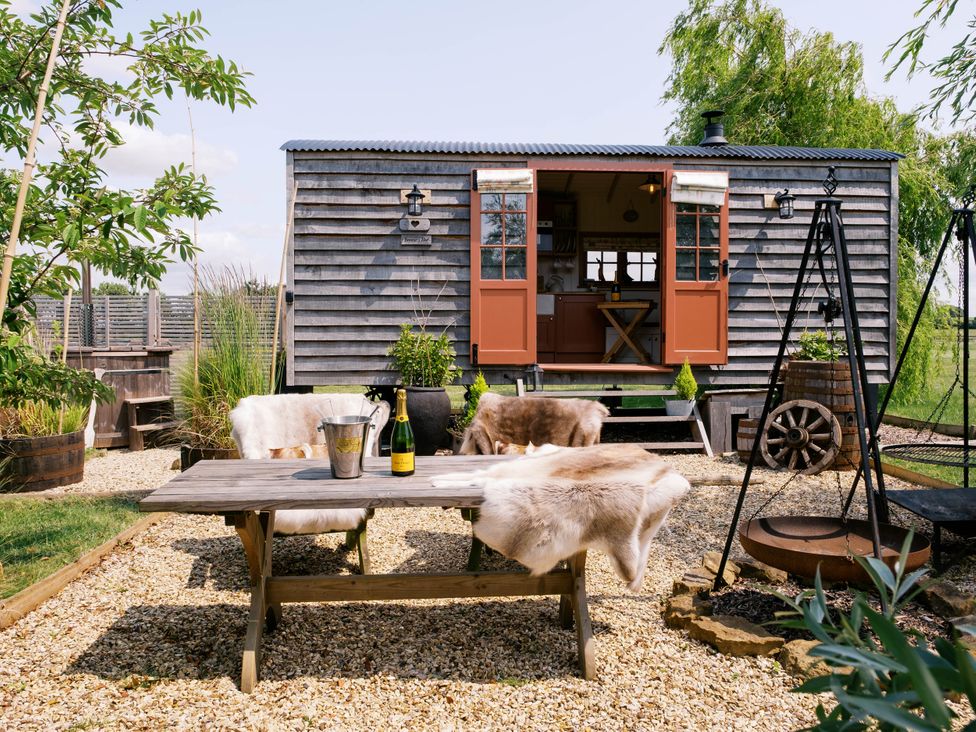 An outdoor area with a table and chairs near a shepherd hut at Bonnie's Shepherds Hut at Shepherds Lodge Retreat and Wellness Bottesford near Redmile and Vale of Belvoir